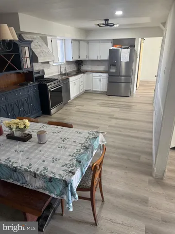 a kitchen with stainless steel appliances kitchen island granite countertop a table chairs sink and stove