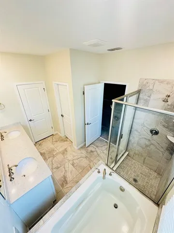 a bathroom with a granite countertop sink and a tub