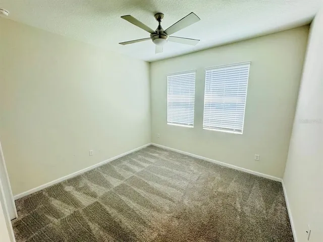 an empty room with windows and fan