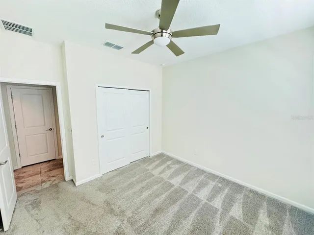 an empty room with a ceiling fan and a window