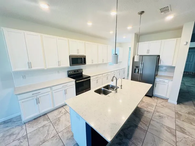 a kitchen with a sink a refrigerator a microwave and cabinets