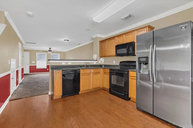 a kitchen with stainless steel appliances kitchen island granite countertop a refrigerator a sink a stove and oven with wooden floor