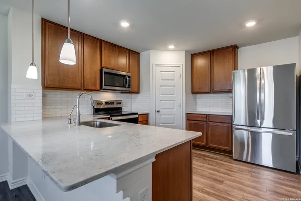 a kitchen with a refrigerator a microwave a sink and cabinets