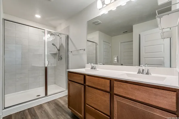 a bathroom with a double vanity sink mirror and shower