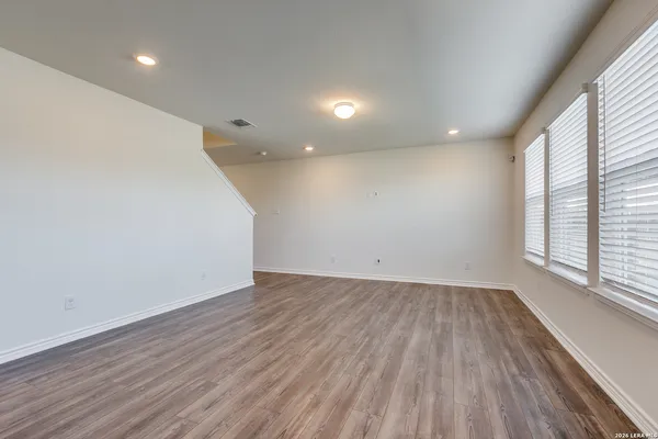 an empty room with wooden floor and windows