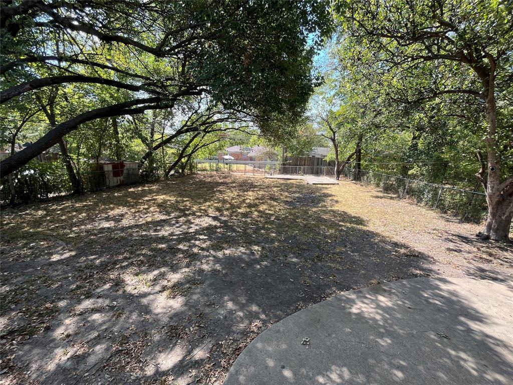 1622 Centerville Road Dallas, TX 75228 - Photo 19 of 19 Expansive outdoor space featuring mature trees, a concrete patio, and chain-link fencing