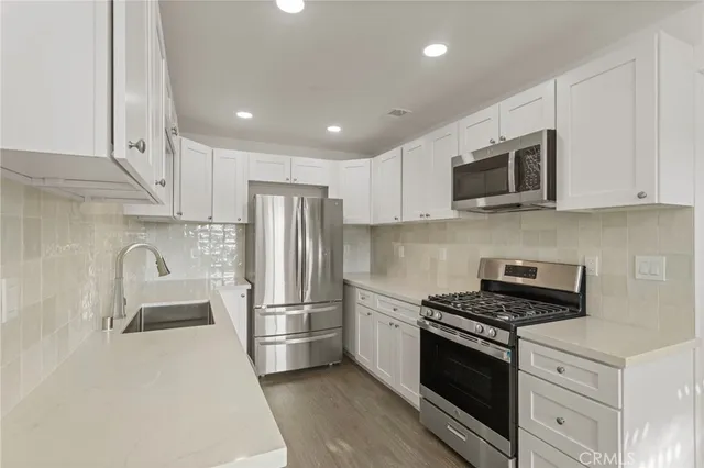 a kitchen with stainless steel appliances granite countertop a refrigerator stove a sink and a microwave