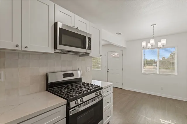 a kitchen with granite countertop a stove and a white cabinets