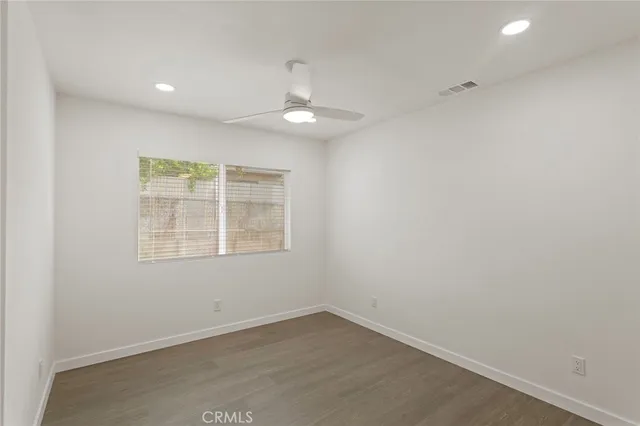 an empty room with a window and chandelier fan