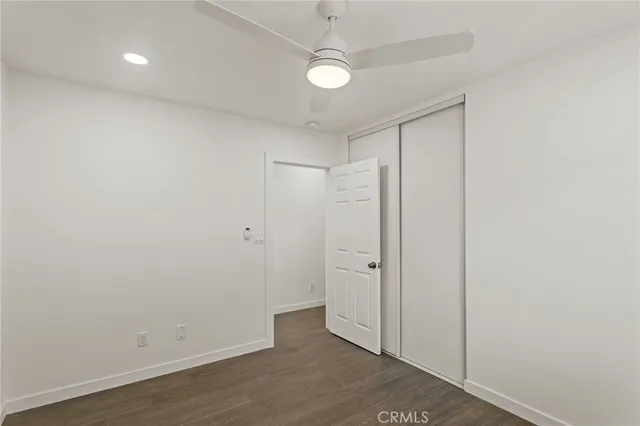 an empty room with wooden floor and a ceiling fan