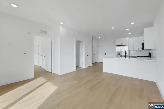 a view of kitchen with refrigerator and white cabinets