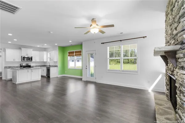 a view of an empty room with kitchen and a window