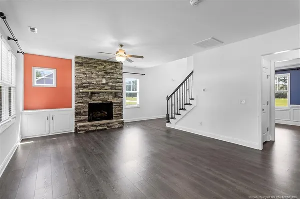 an empty room with wooden floor fireplace and windows