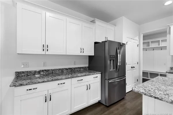a kitchen with granite countertop white cabinets and refrigerator