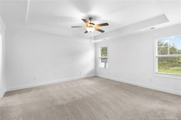 an empty room with windows and fan chandelier fan
