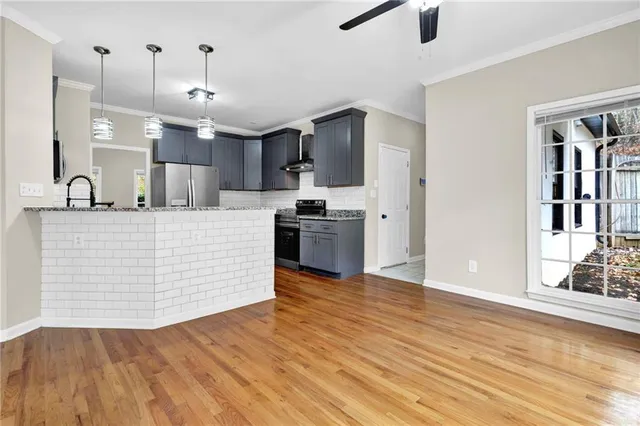 a large kitchen with stainless steel appliances kitchen island a large counter top and wooden floor