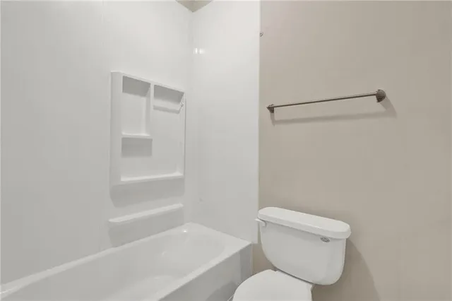 a white toilet sitting next to a bath tub