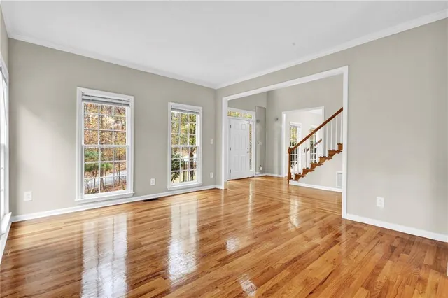 a view of empty room with wooden floor and fan