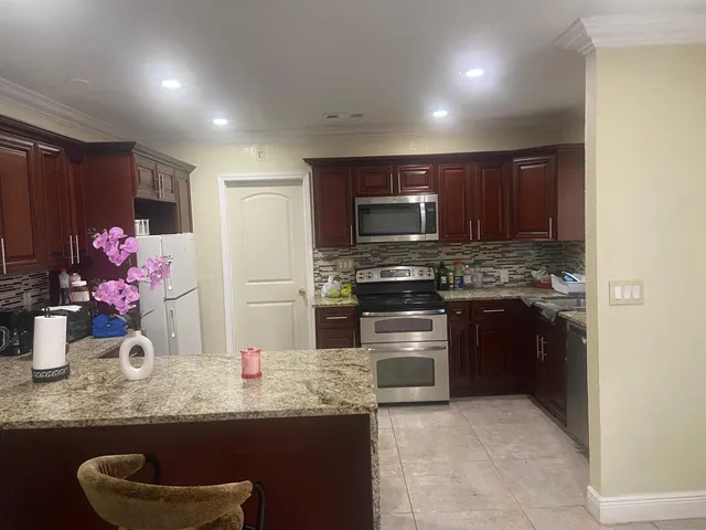 a kitchen with granite countertop a sink cabinets and stainless steel appliances