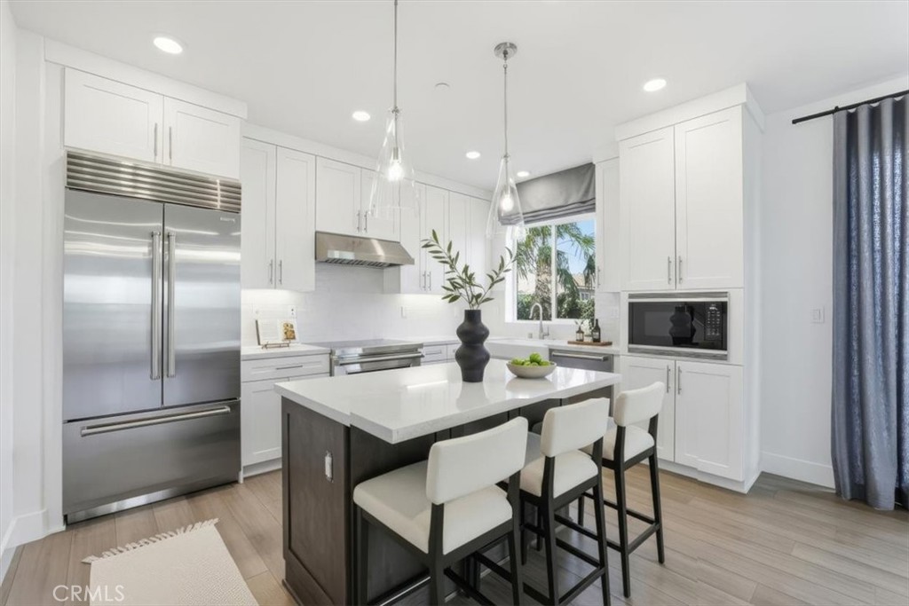 437 Willow Run Lane Carson, CA 90745 - Photo 7 of 37 a kitchen with stainless steel appliances granite countertop a refrigerator a sink a stove a kitchen island and chairs with wooden floor