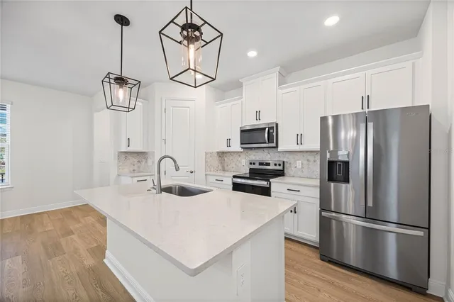 a kitchen with stainless steel appliances a microwave a sink a stove a refrigerator and cabinets