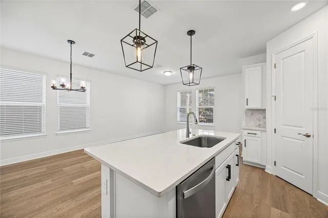 a kitchen that has a sink a refrigerator and chandelier