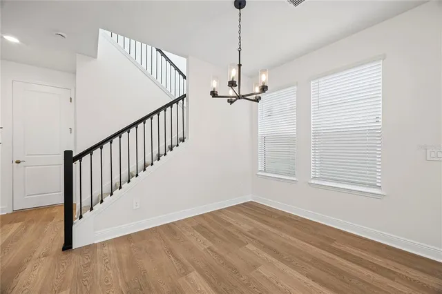 a view of an empty room with wooden floor windows and a chandelier