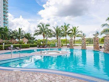2681 North Flamingo Road, Unit 2004S Sunrise, FL 33323 - Photo 17 of 26 a view of a swimming pool with a lawn chairs under palm trees