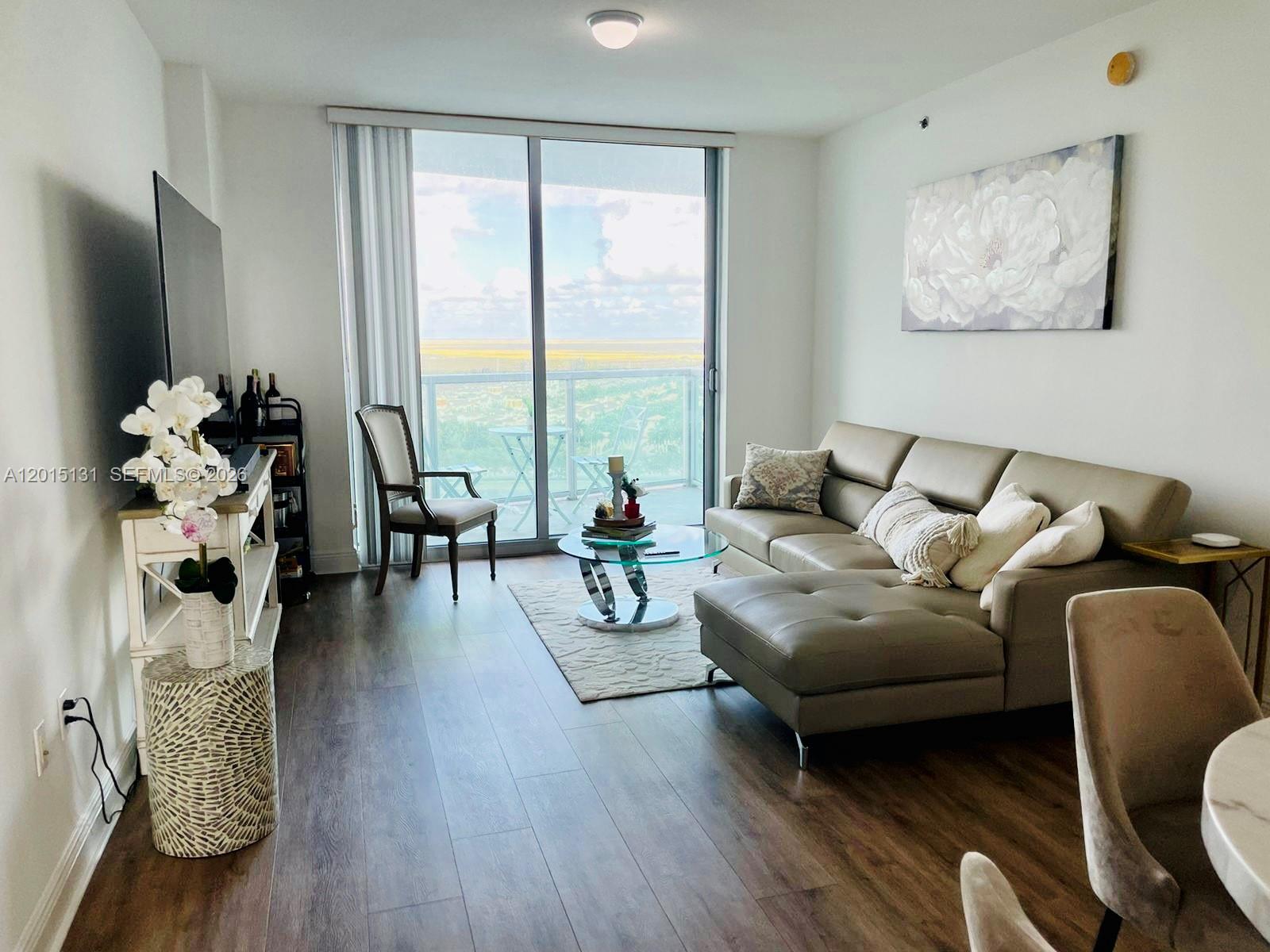 2681 North Flamingo Road, Unit 2004S Sunrise, FL 33323 - Photo 8 of 26 a living room with furniture floor to ceiling window and a flat screen tv
