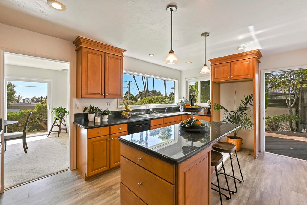 837 Passiflora Avenue Encinitas, CA 92024 - Photo 16 of 42 a kitchen with stainless steel appliances granite countertop a stove top oven a sink a dining table and chairs with wooden floor