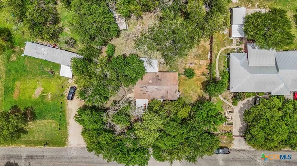 an aerial view of a house with a yard and trees all around