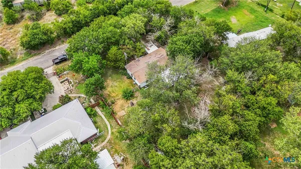 an aerial view of residential house with outdoor space and trees all around