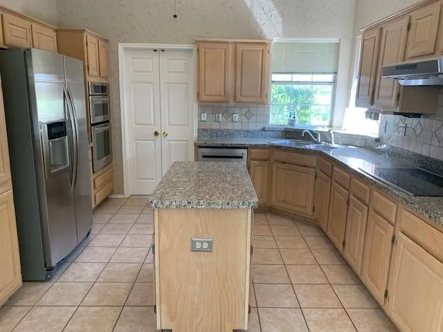 a kitchen with stainless steel appliances granite countertop a refrigerator a sink a stove a microwave and island