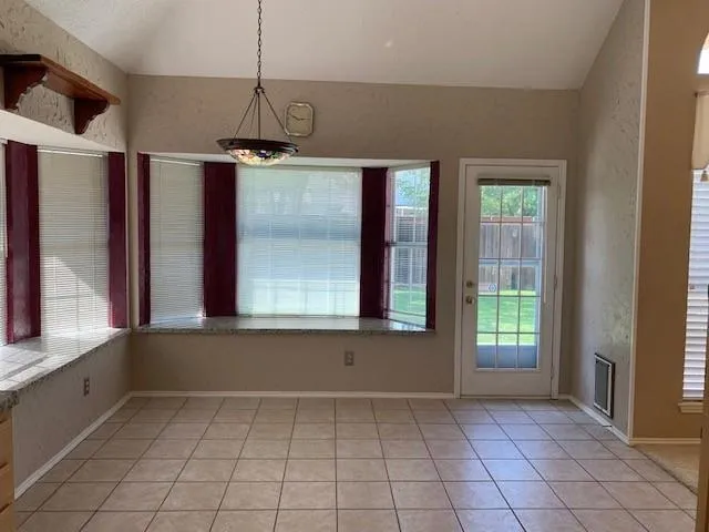 a view of an empty room with window and chandelier fan