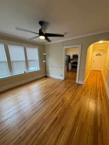 a view of a room with wooden floor ceiling fan and window