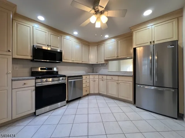 a kitchen with stainless steel appliances granite countertop a refrigerator a stove a sink and a microwave