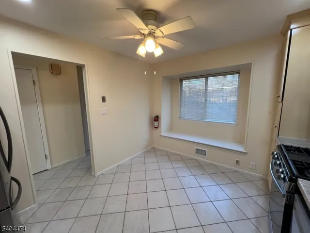 a view of an empty room with window and chandelier fan