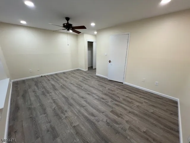 an empty room with a ceiling fan and wooden floor