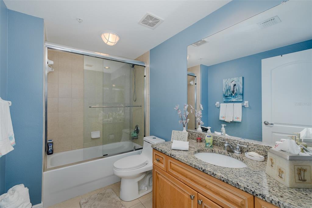4516 Seagull Drive, Unit 615 New Port Richey, FL 34652 - Photo 19 of 45 a bathroom with a granite countertop sink a toilet a mirror a bathtub and shower