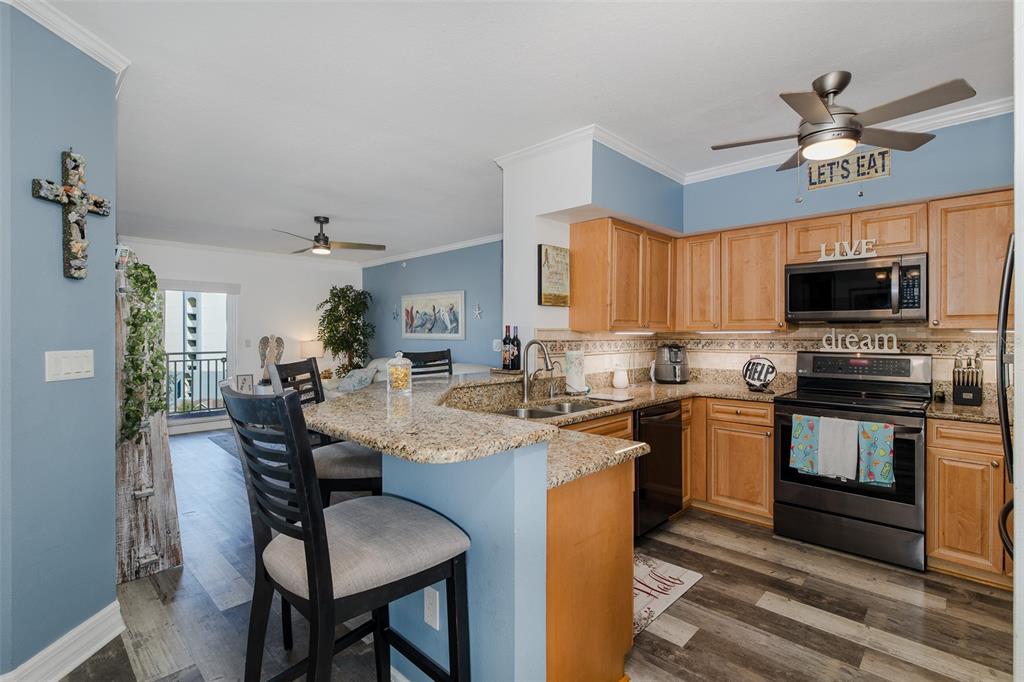 4516 Seagull Drive, Unit 615 New Port Richey, FL 34652 - Photo 8 of 45 a kitchen with stainless steel appliances granite countertop a stove top oven a sink dishwasher a dining table and chairs with wooden floor