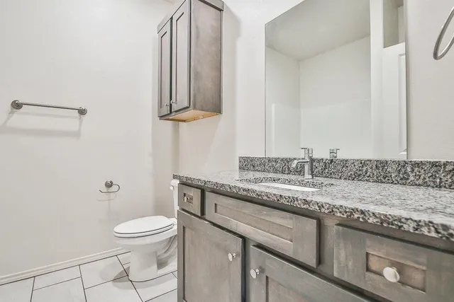 a bathroom with a granite countertop toilet sink and mirror