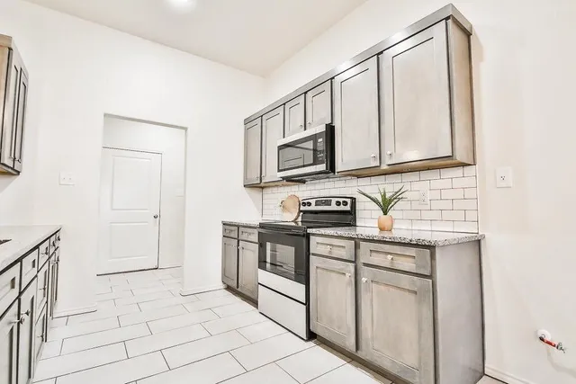 a kitchen with stainless steel appliances granite countertop a stove a sink and a microwave