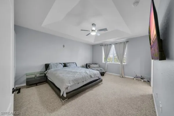 a spacious bedroom with a bed and a flat tv screen on the dresser