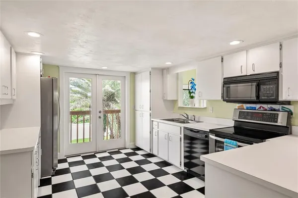 a kitchen with stainless steel appliances a stove a sink a refrigerator and a window