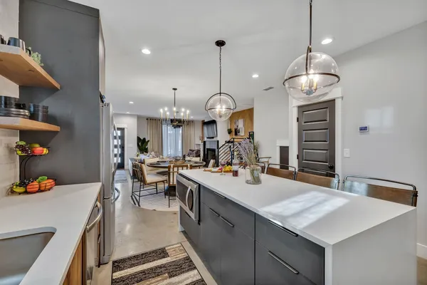 a large kitchen with kitchen island a stove a table a sink a refrigerator and living room view