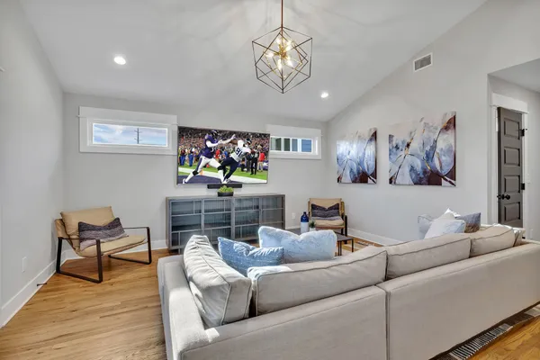 a living room with furniture a chandelier and a flat screen tv