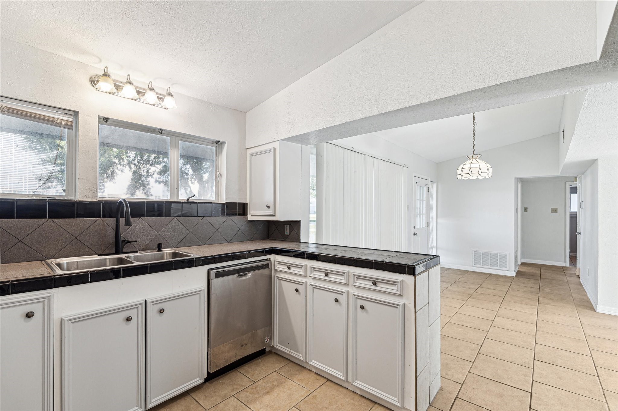 5125 Maple Street Bellaire, TX 77401 - Photo 5 of 14 a kitchen with a sink dishwasher a stove and white cabinets with wooden floor