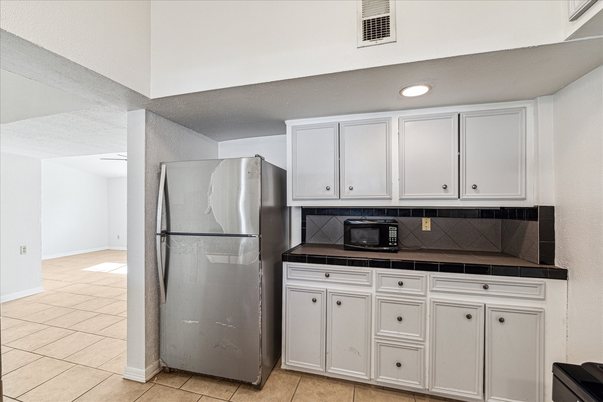 5125 Maple Street Bellaire, TX 77401 - Photo 6 of 14 a kitchen with granite countertop white cabinets and refrigerator