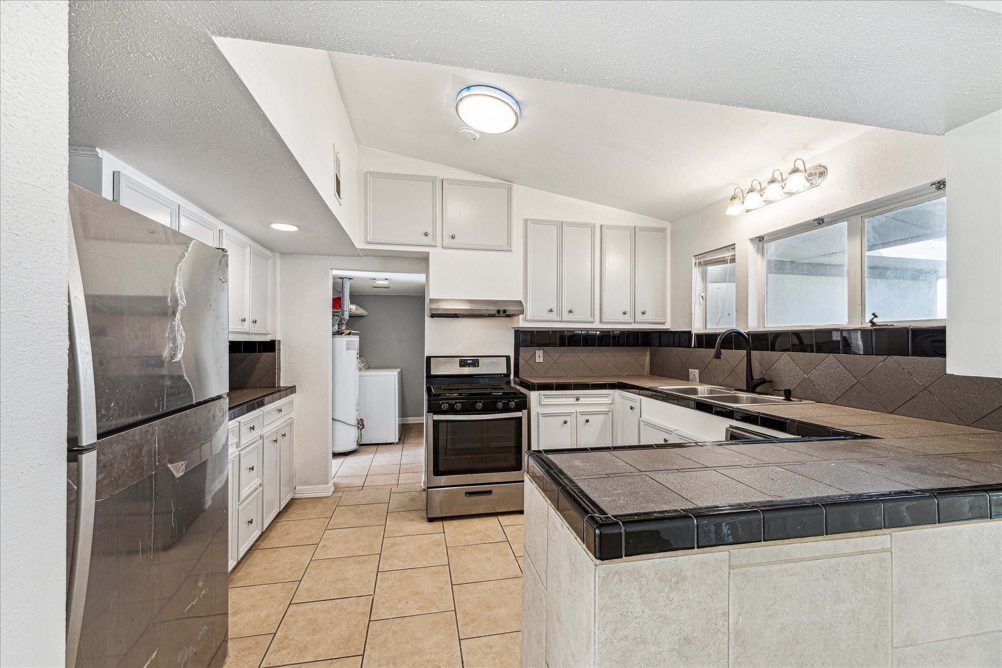 5125 Maple Street Bellaire, TX 77401 - Photo 7 of 14 a kitchen with granite countertop a refrigerator a sink and white cabinets