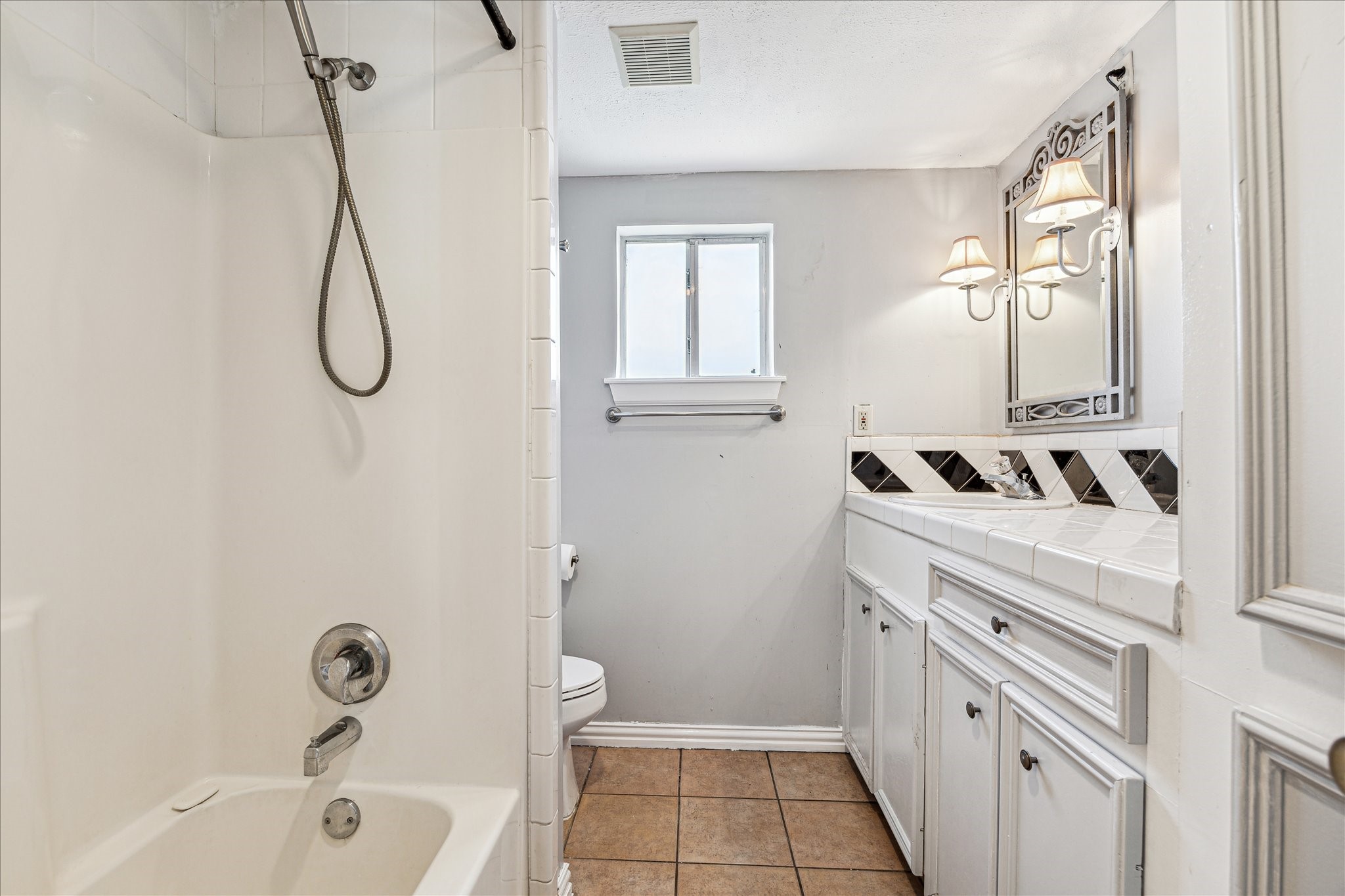 5125 Maple Street Bellaire, TX 77401 - Photo 10 of 14 a bathroom with a granite countertop sink a toilet and a bathtub